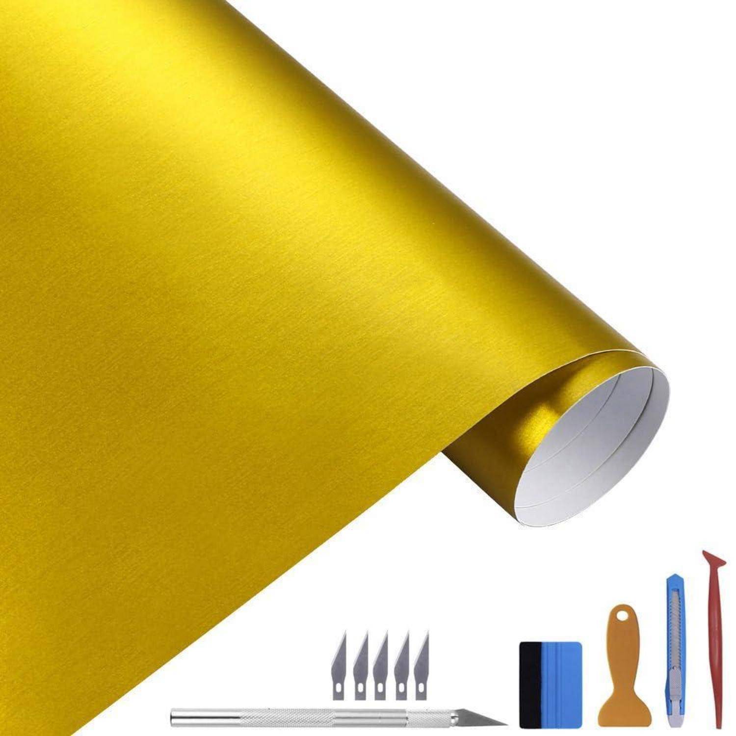 Goldenes Klebevinylblatt mit Handwerkswerkzeugen, einschließlich Universalmessern und Rakel, auf weißem Hintergrund angeordnet.