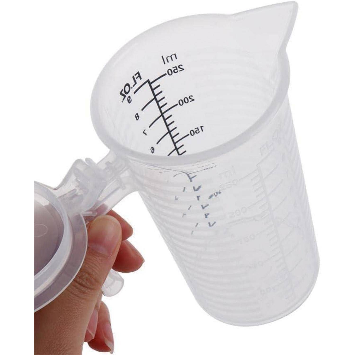 Transparenter Messbecher aus Kunststoff mit aufklappbarem Deckel und Griff, mit Markierungen in Milliliter und Flüssigkeitsunzen, in einer Hand gehalten.