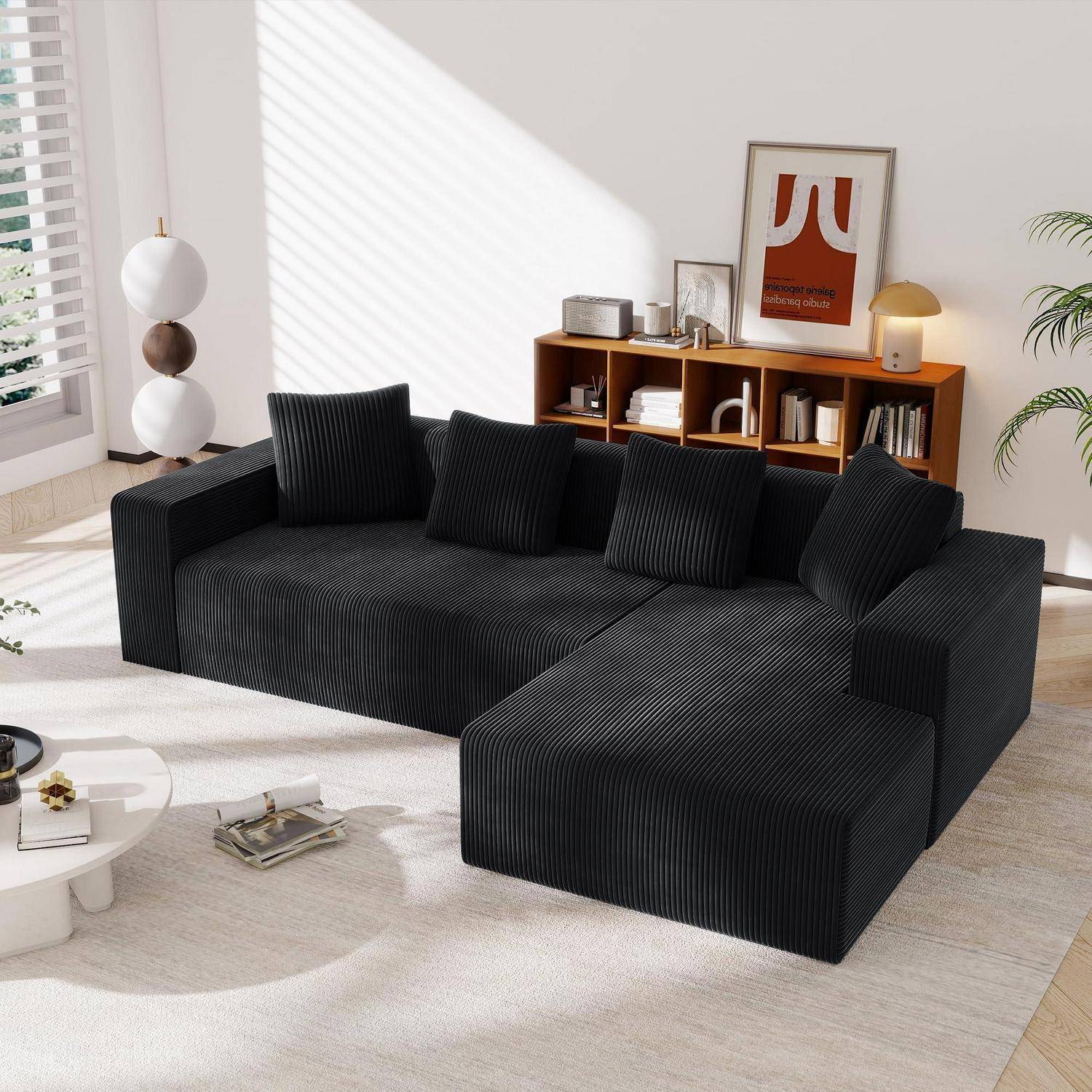 Modernes Wohnzimmer mit schwarzem Ecksofa, gestreiften Kissen, Holzregal, Stehleuchte und abstraktem Wandgemälde in heller Sonneneinstrahlung.