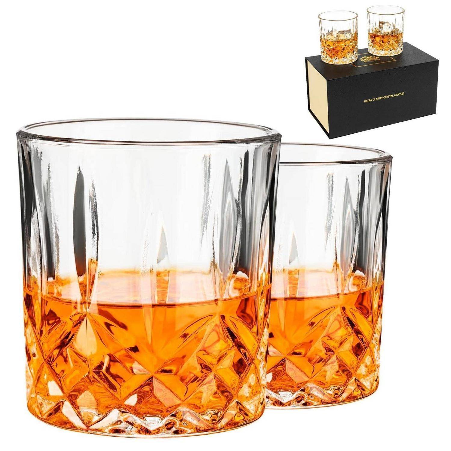 Satz von zwei facettierten Whiskeygläsern mit bernsteinfarbener Flüssigkeit, dargestellt mit einer Geschenkbox als Einsatz in der Ecke.