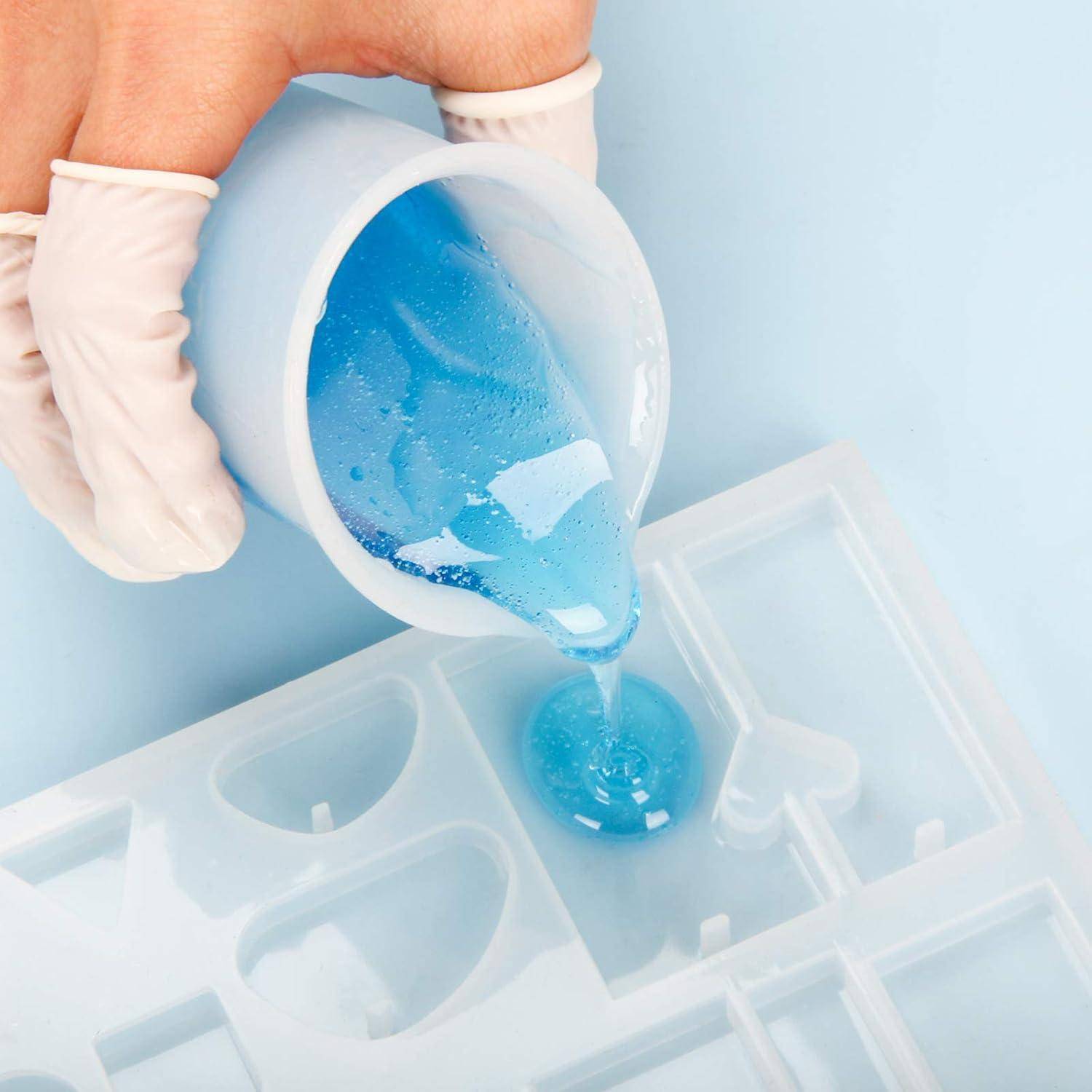 Behandschuhte Hände gießen blaues Harz in eine Silikonformschale zum Handwerk oder Gießen.