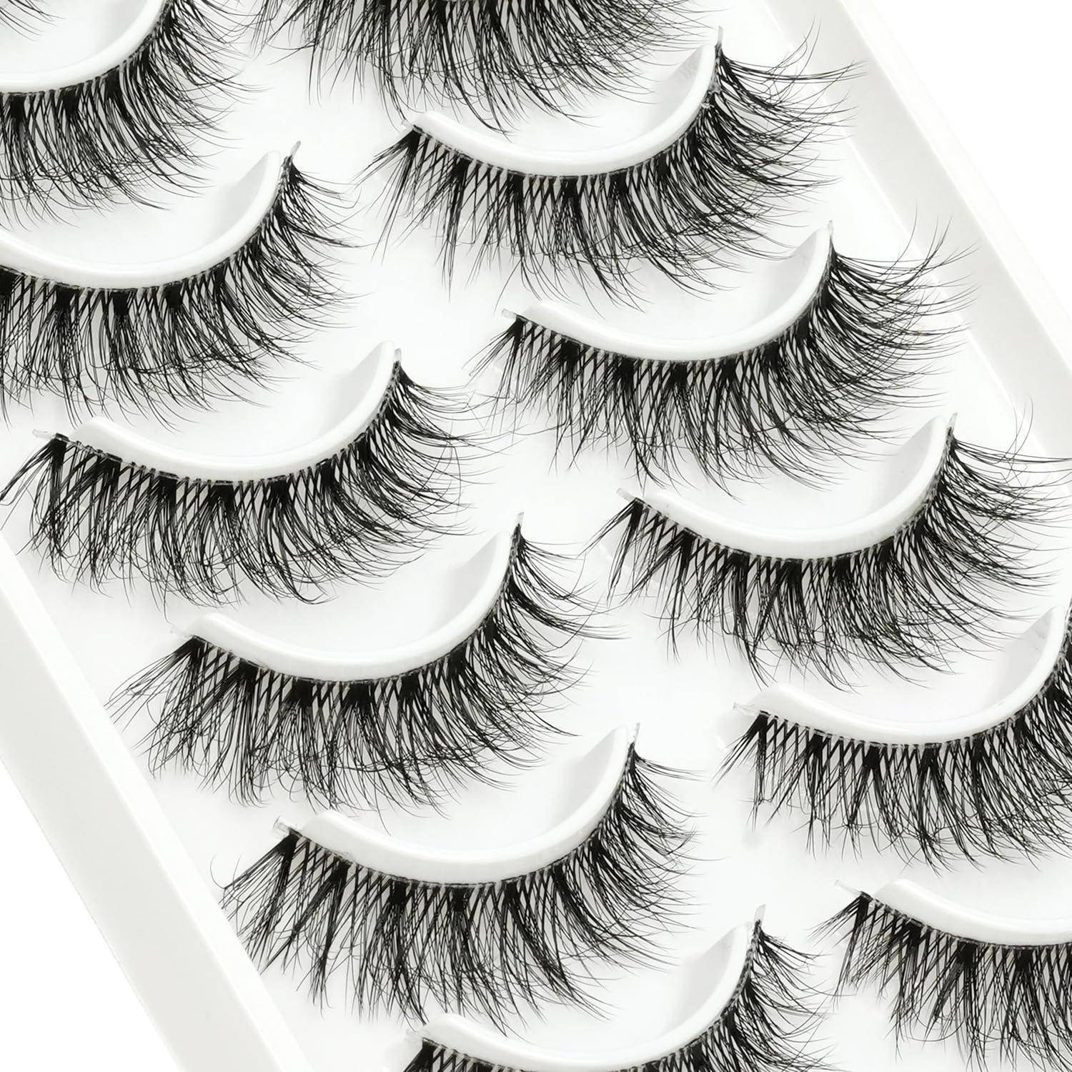 Nahaufnahme mehrerer Wimpernstreifen aus künstlichen Wimpern, die in einem weißen Tablett angeordnet sind und lange, wehende schwarze Wimpern zeigen.