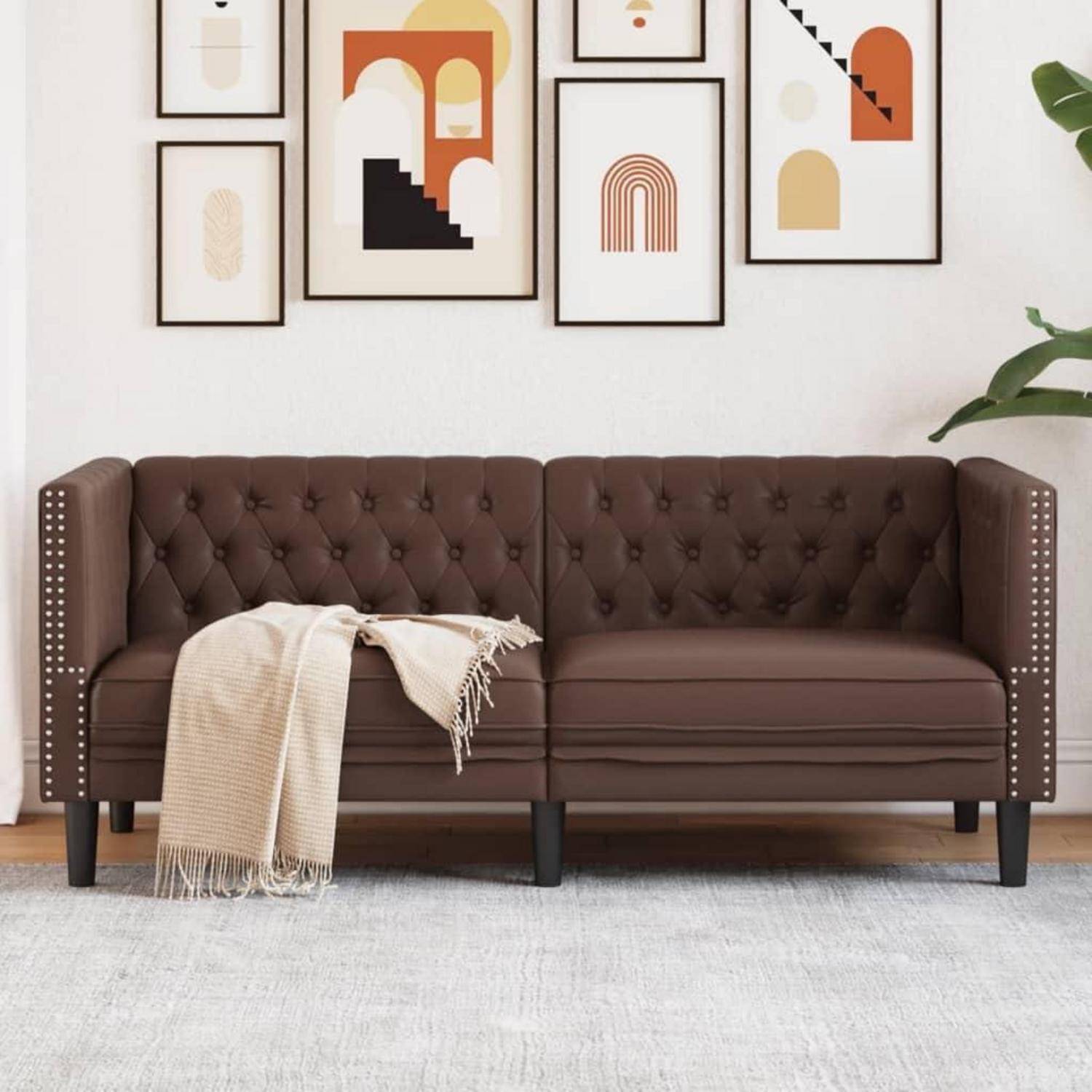 Braunes Polstersofa mit Quasten und eine beige Wurfdecke, vor gerahmter abstrakter Wandkunst in einem hellen, modernen Wohnzimmer.
