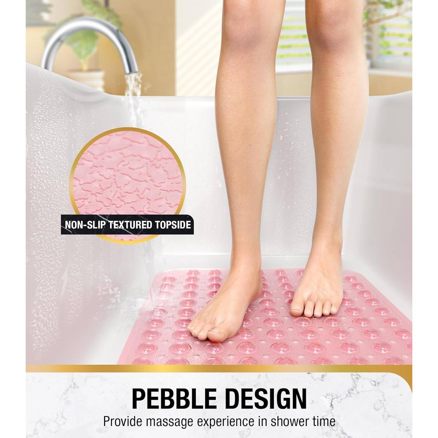 Person steht auf einer rosa Kiesel-strukturierten Badmatte in einer Dusche, gekennzeichnet mit „Pebble Design" und „Rutschfeste strukturierte Oberseite"" für Massage und Grip.