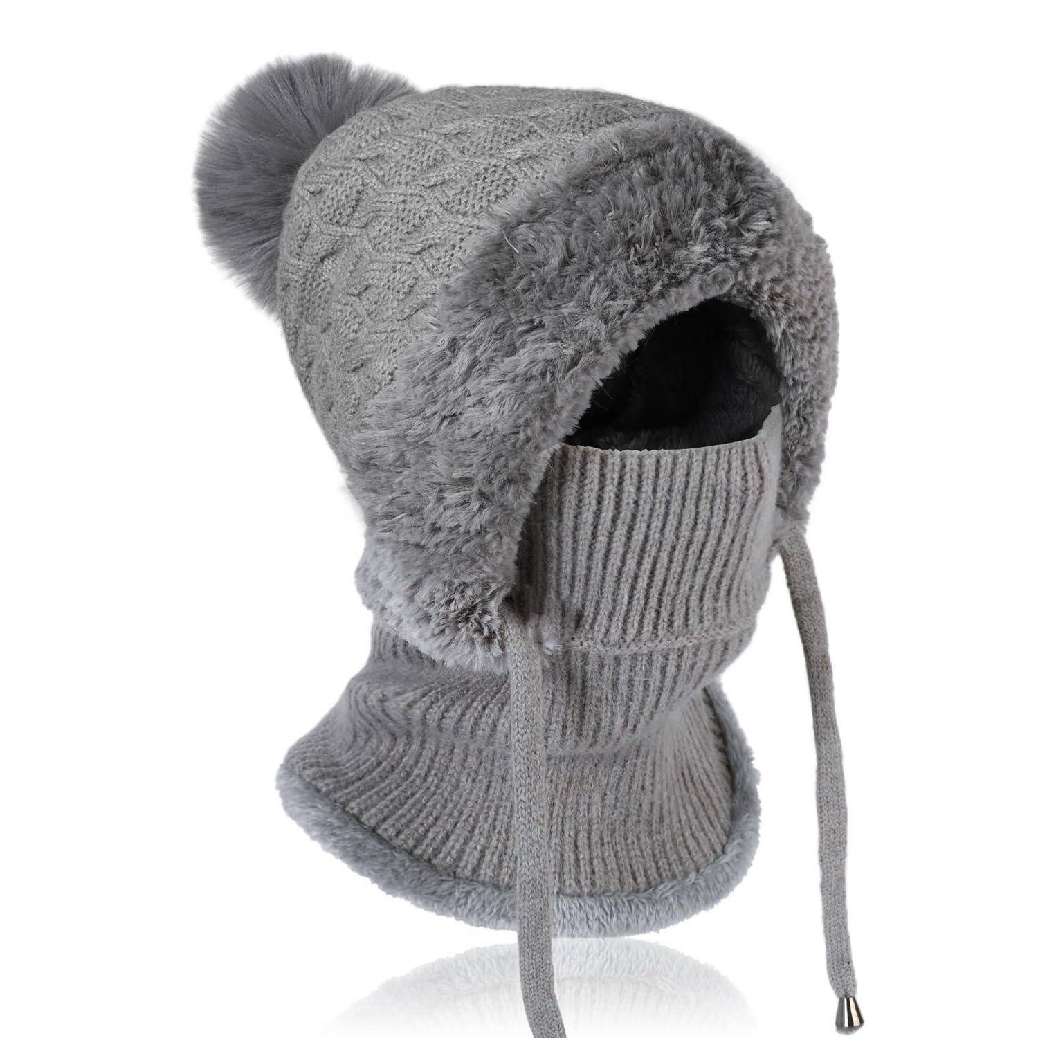 Graue Strickwollmütze für den Winter mit Kunstfellbesatz, Pompon und baumelnden Bändern, isoliert auf weißem Hintergrund dargestellt.