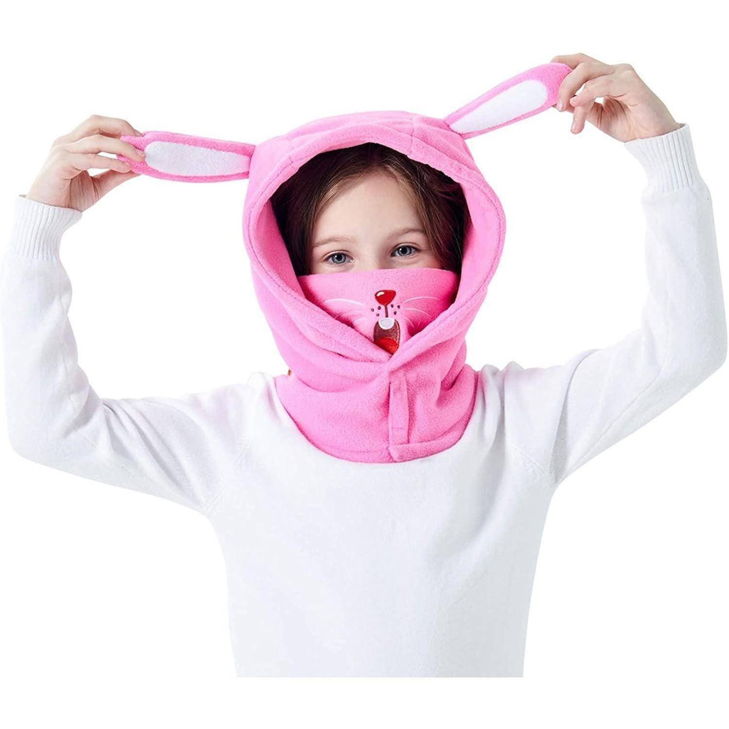 Kind, das eine rosa tierfarbige Gesichts- und Kopfbedeckung mit Ohrenklappen trägt, hält die Ohren hoch, vor weißem Hintergrund.