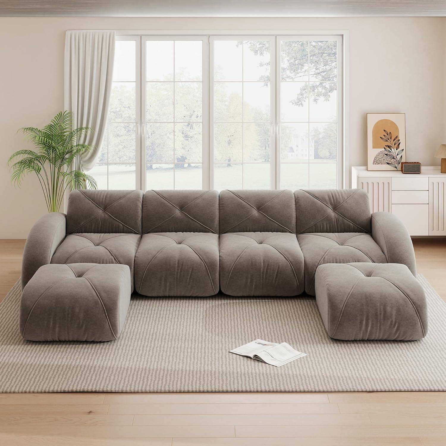 Modulares Taupe-Sofa mit passenden Ottomanen in einem hellen Wohnzimmer, dargestellt auf einem hellen Teppich vor großen Fenstern und Pflanzen.