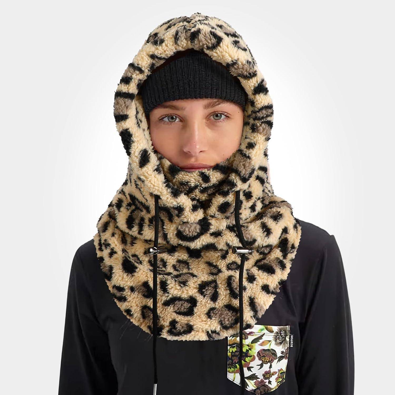 Person trägt eine Leoparden-Muster-Kapuzen-Sturmmaske über einer schwarzen Mütze und schwarzem Oberteil, die den Kopf und Nacken gegen kaltes Wetter schützen.