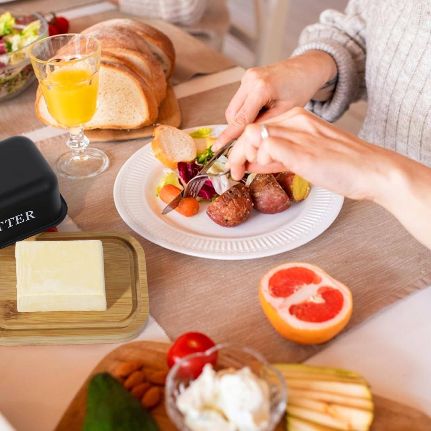 Hände präsentieren ein Brunches Essen aus Steak, Gemüse und Brot auf einem Tisch mit Orangensaft, Butter, Grapefruit und Obst.