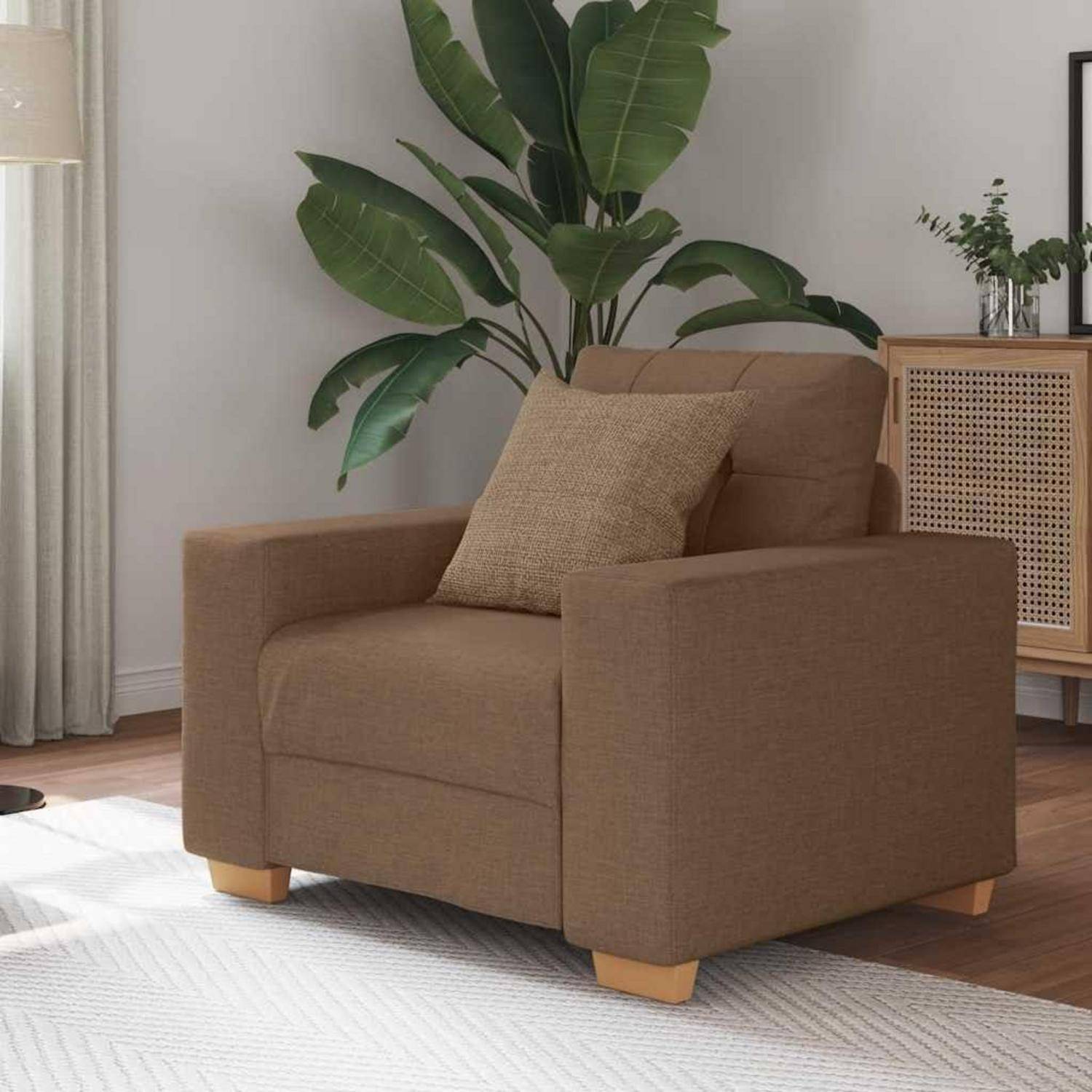 Brauner gepolsterter Sessel mit passendem Kissen in einem modernen Wohnzimmer, neben einer großen Topfpflanze und einem Holzschrank.