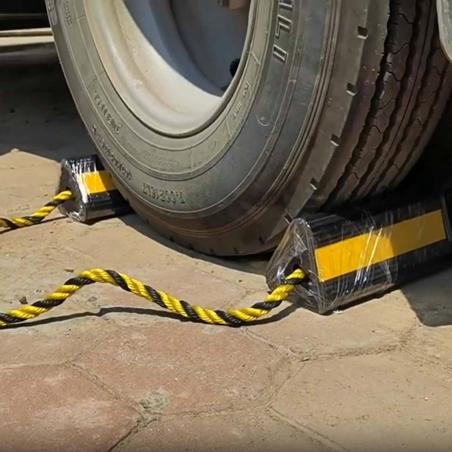 Lastwaggen-Rad gesichert auf gelb-schwarzen Radkeilen mit einem verdrehten Seil oder Kabel zwischen ihnen auf Beton.