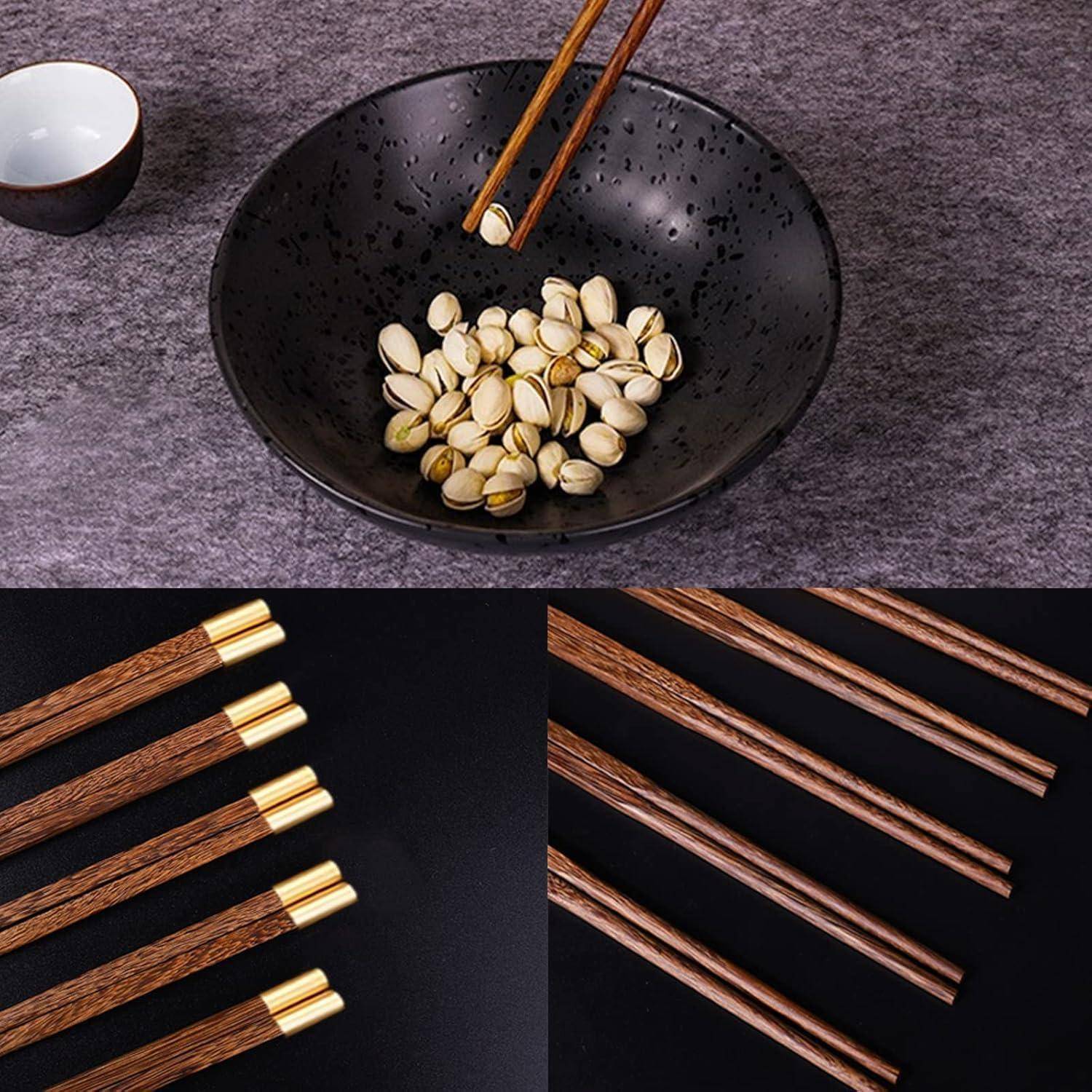 Wiederverwendbare Essstäbchen mit Holzmaserung und Goldspitzen, gezeigt in einer Schüssel mit Pistazien und in Nahaufnahme vor schwarzem Hintergrund.