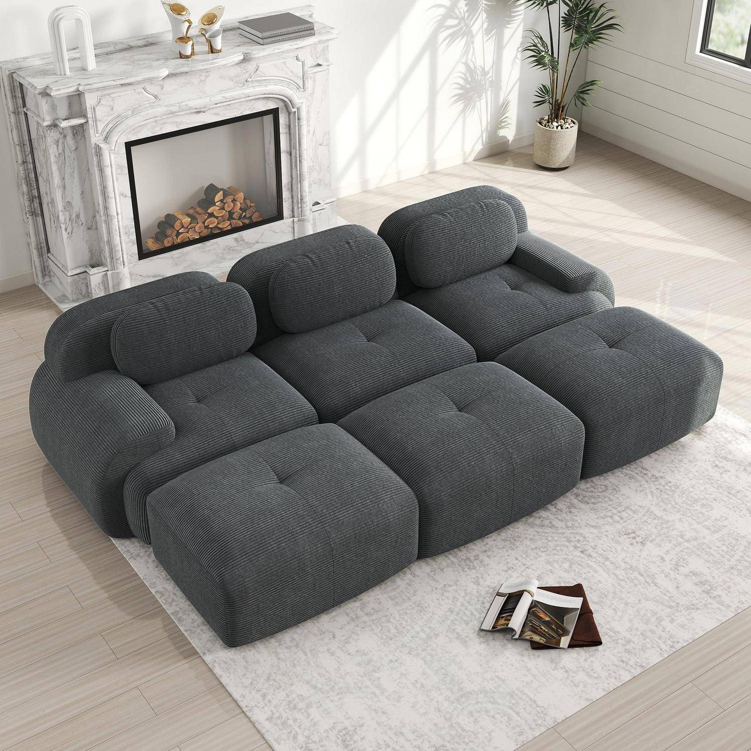 Dunkelgraues modulares gestepptes Sofa in einem hellen Wohnzimmer mit Marmorkamin und Teppich