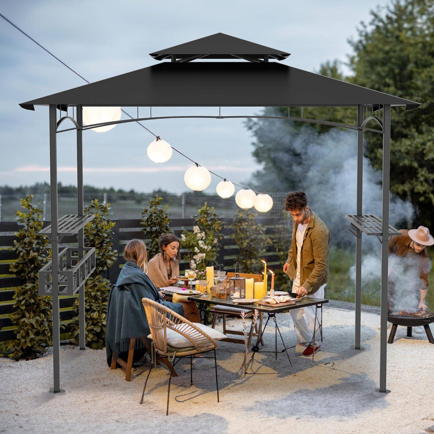 Menschen versammeln sich zu einem Outdoor-Abendessen unter einem Pavillon mit hängenden Lichtern, sitzen an einem Tisch, während eine Person in der Nähe grillt.