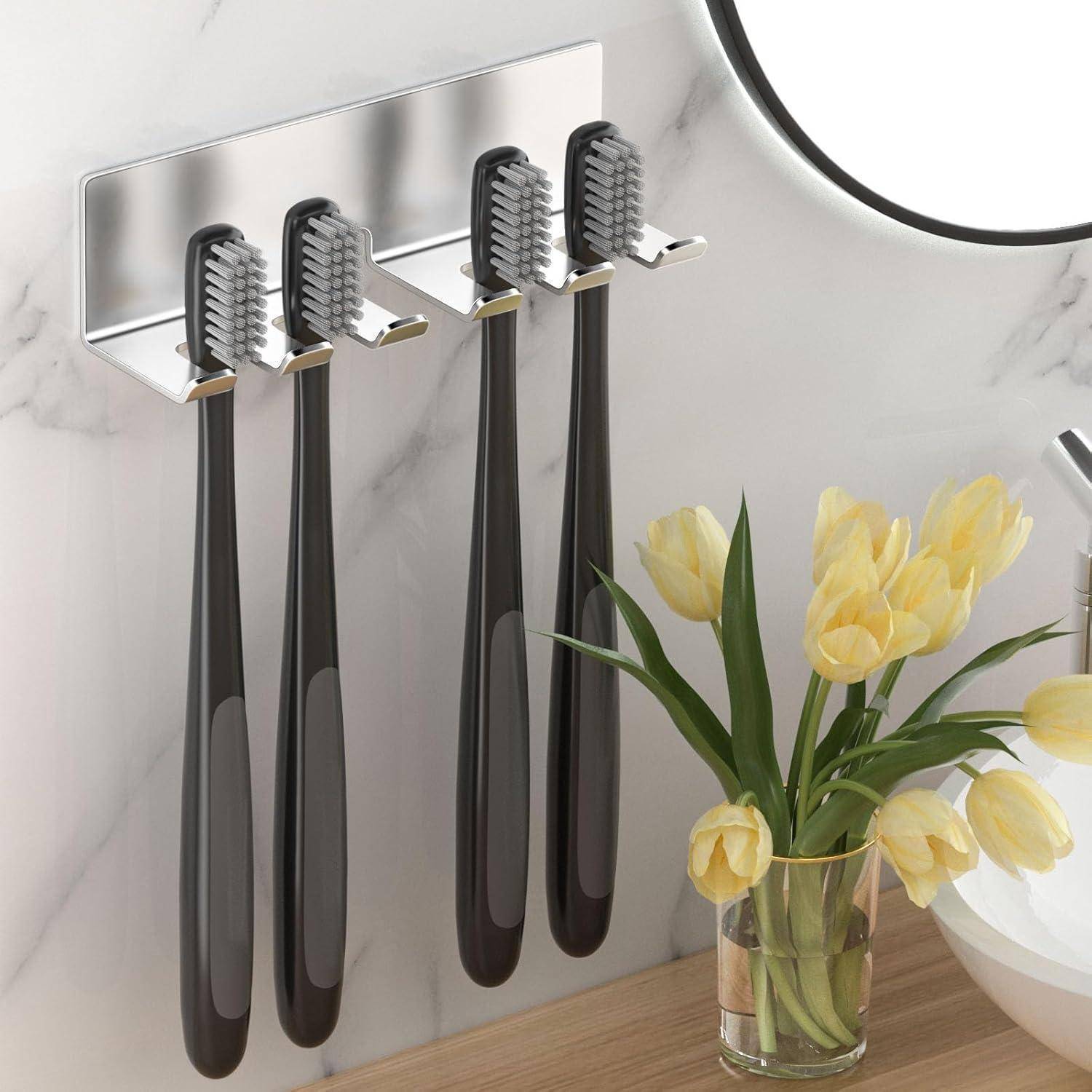 Wandmontierter Zahnbürstenhalter mit vier schwarzen Zahnbürsten und einer kleinen Vase mit gelben Tulpen auf einer Arbeitsplatte neben einem Spiegelbadezimmerschrank.
