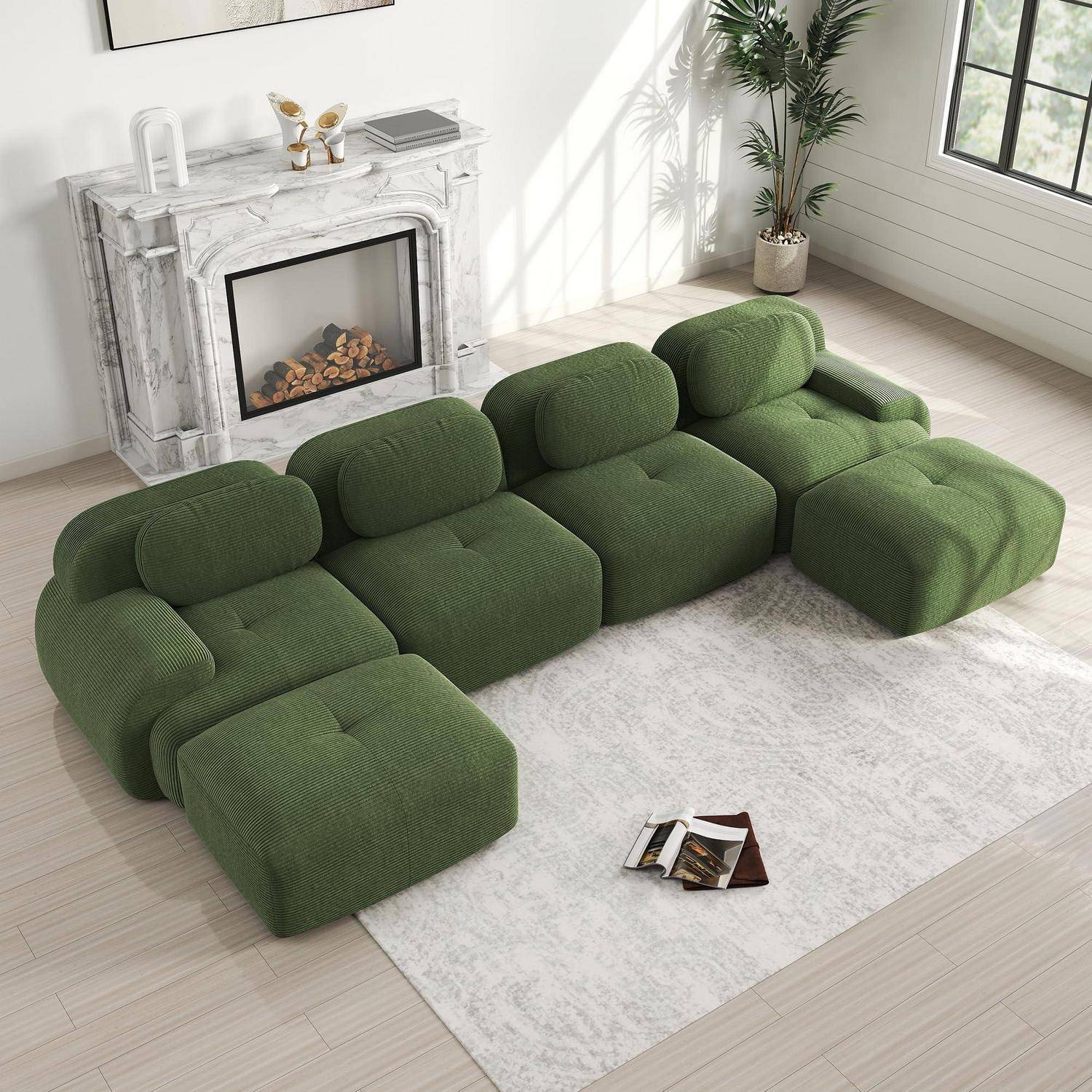 Grünes modulares Ecksofa mit übergroßen Kissen in L-Form auf einem hellen Teppich in einem hellen Wohnzimmer neben einem Marmorkamin.