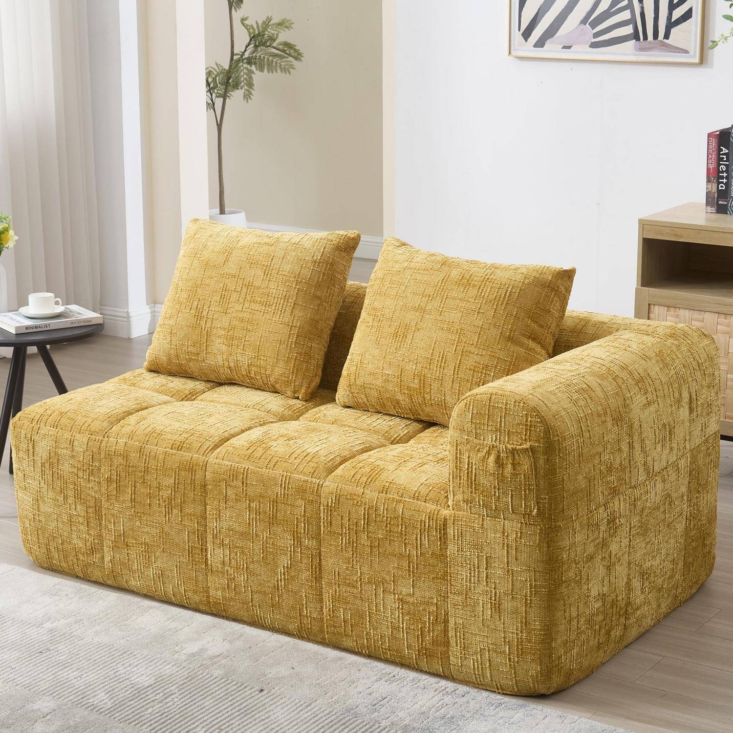 Senfsgelbes strukturiertes Zweisitzer-Sofa mit zwei Rückenkissen in einem hellen Wohnzimmer, von vorne links gezeigt.