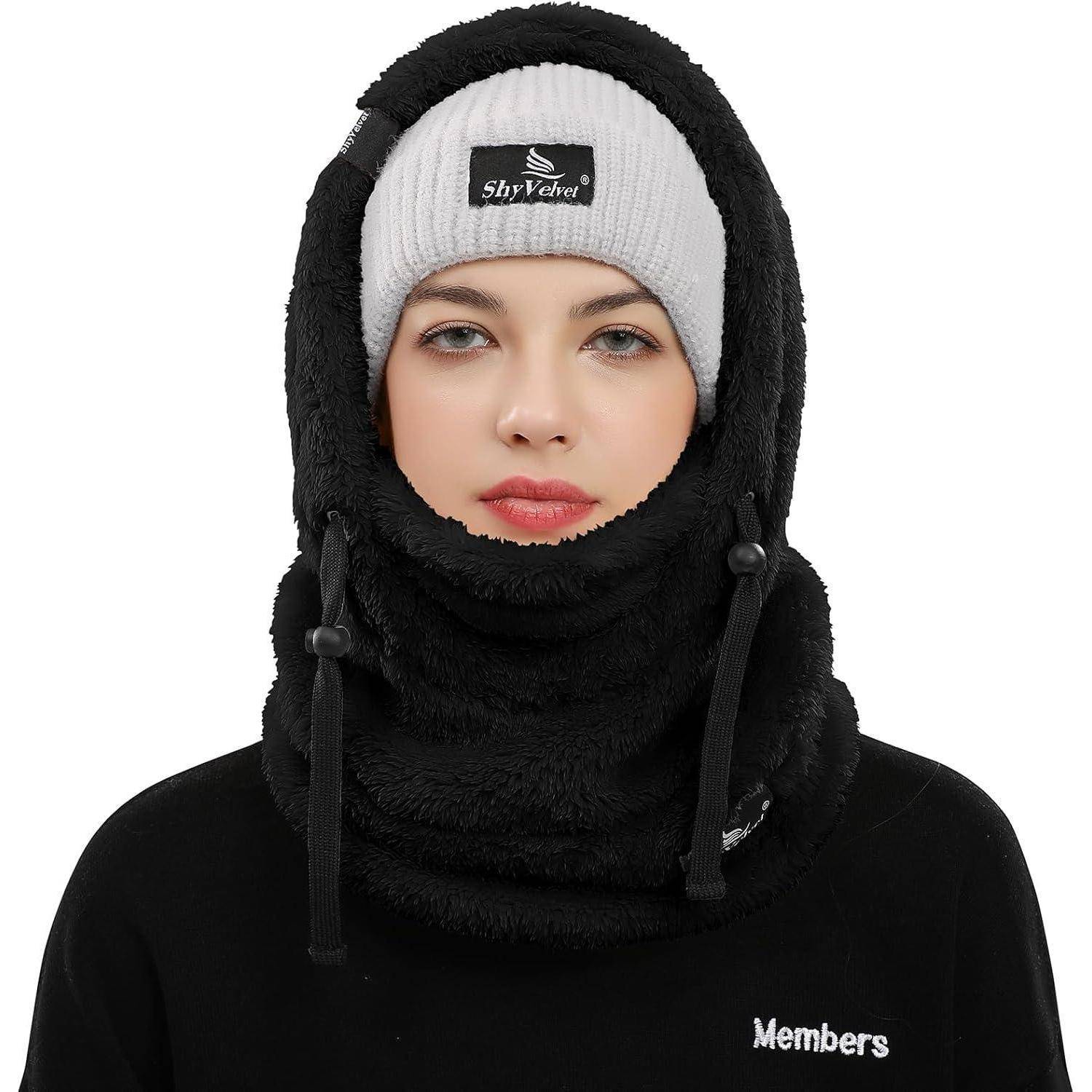 Eine Person, die eine schwarze Fleece-Balaklava und eine graue Beanie trägt, mit nur dem sichtbaren Gesicht vor einem weißen Hintergrund.