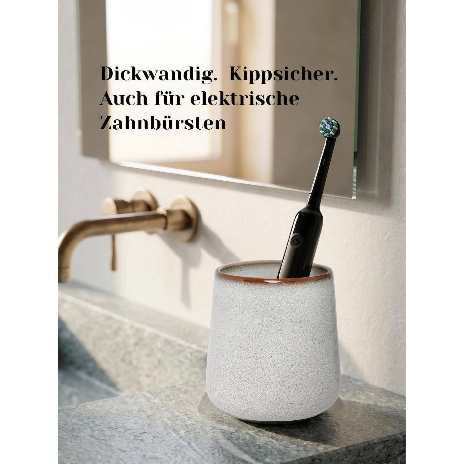 Elektrische Zahnbürste in einem beschwerten weißen Ständer neben einem Badezimmerspülbecken, mit deutschem Text, der besagt: „Dickwandig. Kippfest. Auch für elektrische Zahnbürsten.