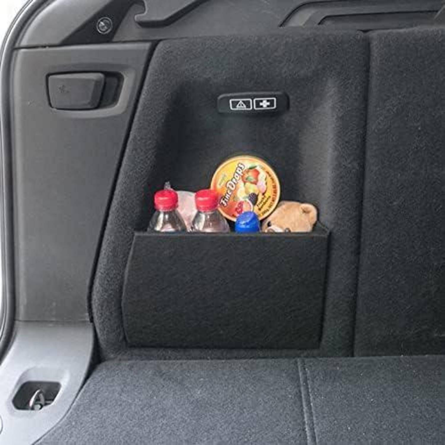 Rücksitztasche des Autos mit zwei kleinen Flaschen, einer blauen Kappe, einer Snack-Box und einem Plüschtier
