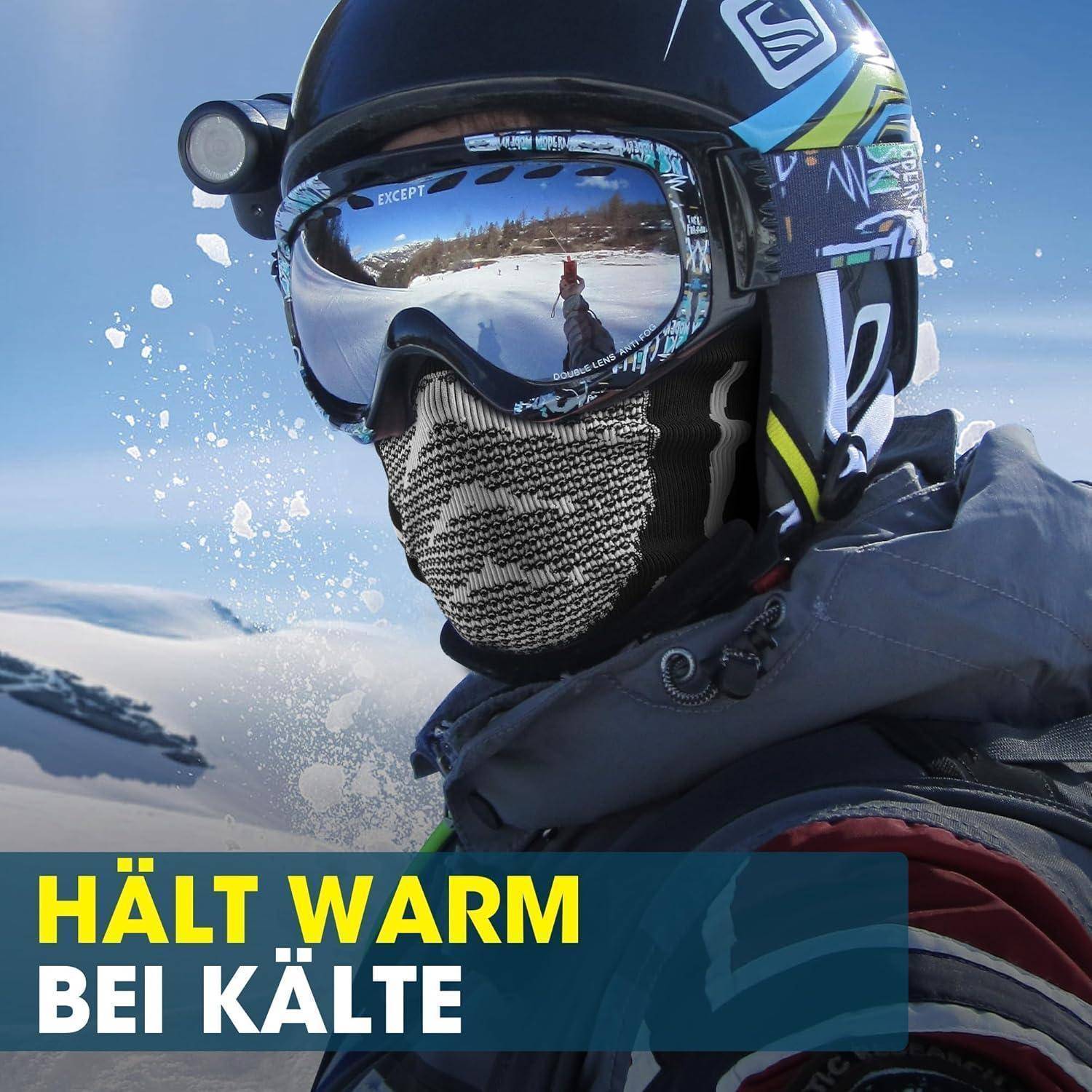 Skifahrer mit Helm, Schutzbrille und Gesichtsschutz bei verschneiten Bedingungen mit dem Text „HÄLT WARM BEI KÄLTE