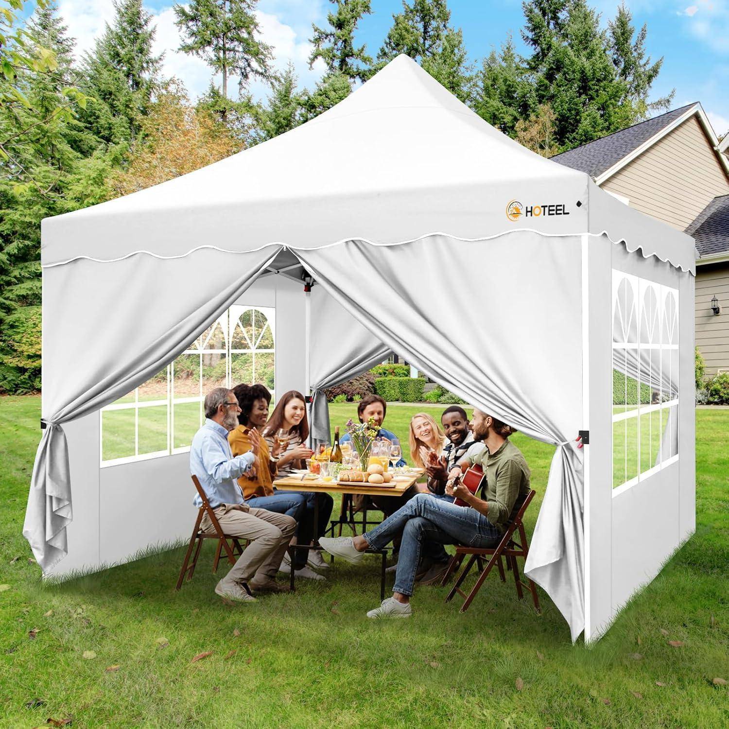 Menschen sitzen um einen Tisch herum, essen und unterhalten sich in einem weißen Außenbereich-Pavillon im Hinterhof.