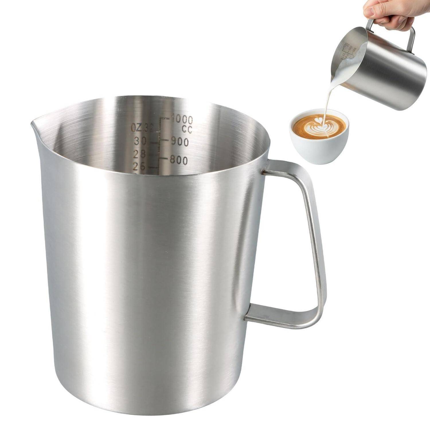 Edelstahlmessbecher mit Griff und Ausgießer, gezeigt mit Milch, die in eine kleine Kaffeetasse gedämpft wird.