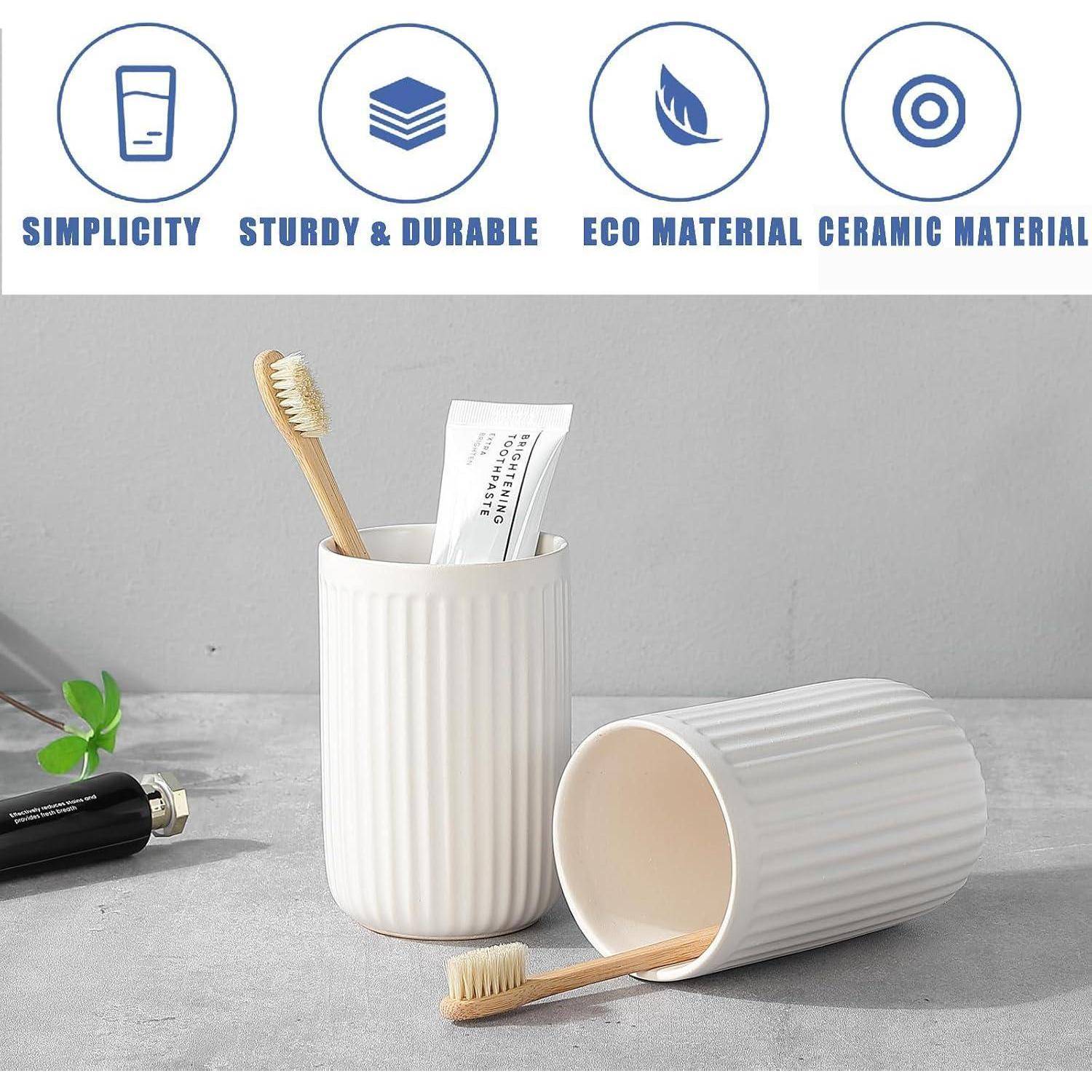 Zwei weiße gerillte Keramik-Zahnputzbecher für das Badezimmer, einer aufrecht stehend und einen Zahnpinsel sowie eine Tube haltend, einer auf der Seite liegend; Symbole oben zeigen Einfachheit, robust und langlebig, Ökomaterial, Keramikmaterial.