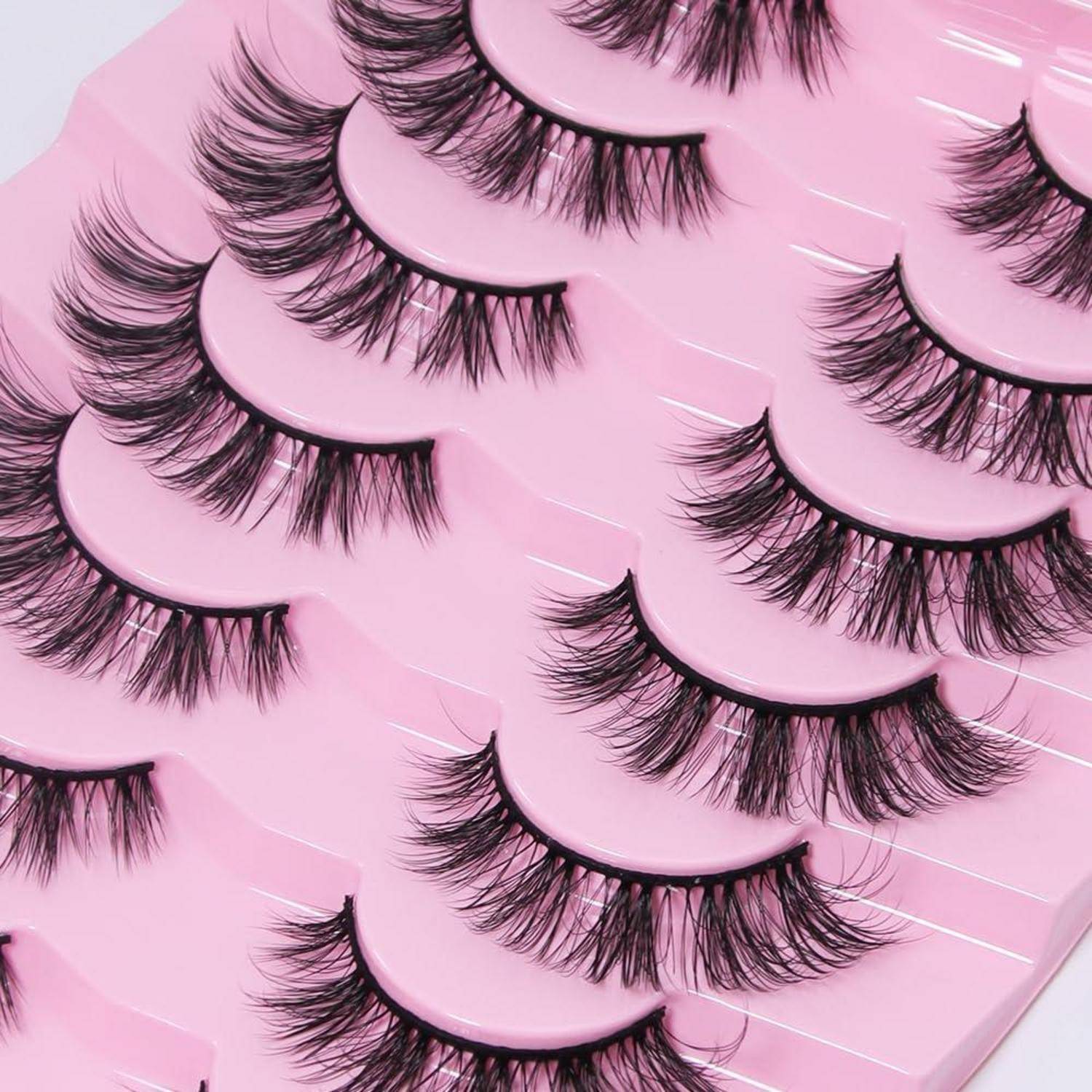 Sortierte künstliche Wimpern auf rosa Verpackungskarten in einer Nahaufnahme-Produktanordnung.