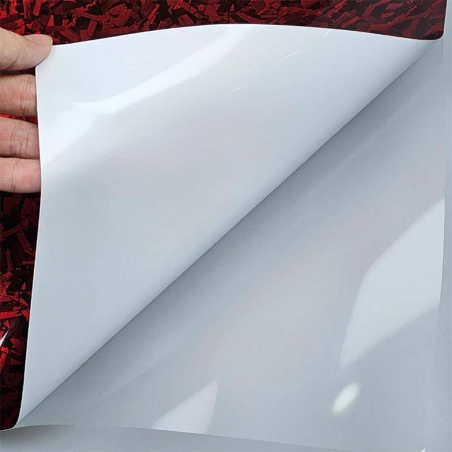 Hand, die ein weißes Haftungsblatt von einer roten strukturierten Oberfläche abzieht und das Material darunter freilegt.