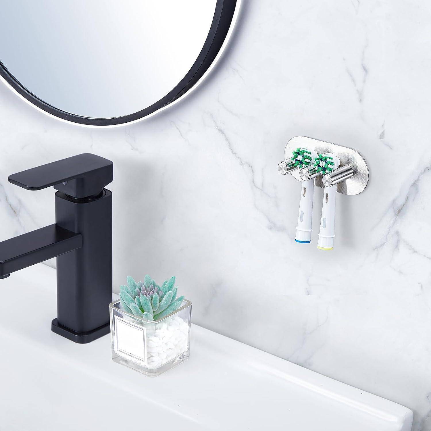 Badezimmerwaschbereich mit schwarzem Wasserhahn, rundem Spiegelrand, Zahnbürstenhalter an der Wand und kleine Sukkulente auf der Arbeitsplatte.