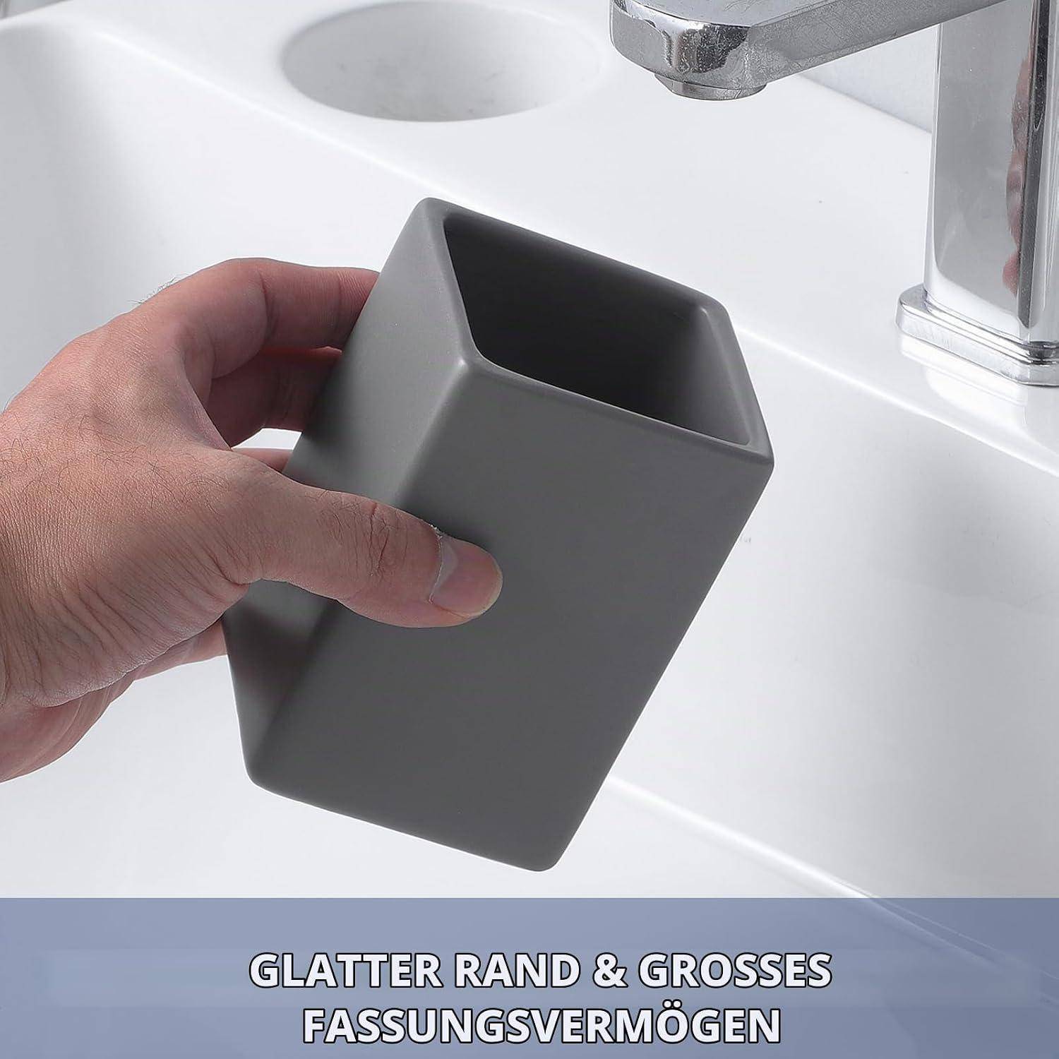 Eine Hand hält einen grauen quadratischen Becher über einem weißen Waschbecken und zeigt die glatten Kanten und Fassungsvermögen des Bechers.