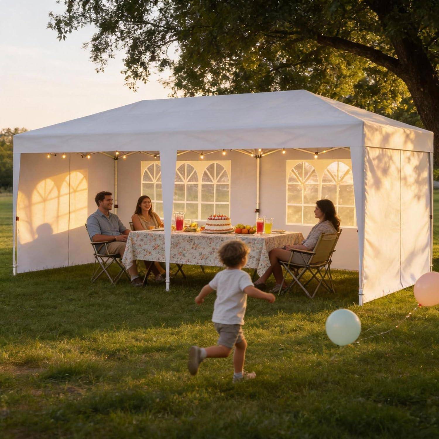 Familientreffen unter einem weißen Baldachindach im Freien bei Sonnenuntergang, mit drei Erwachsenen, die an einem dekorierten Tisch sitzen, und einem Kind, das im Vordergrund herumläuft.