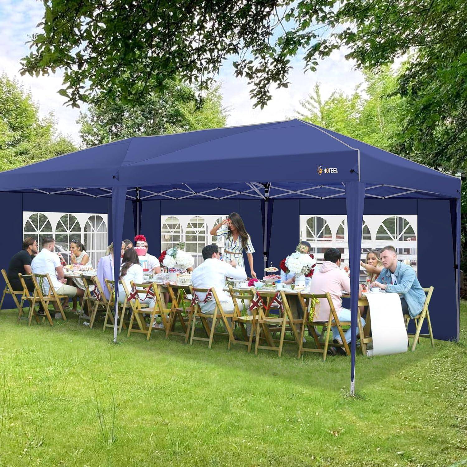 Personen, die an einem langen Tisch im Freien unter einem großen dunkelblau gefärbten Baldachindach in einem Garten mit Rasen sitzen, während ein Kellner unter ihnen steht.