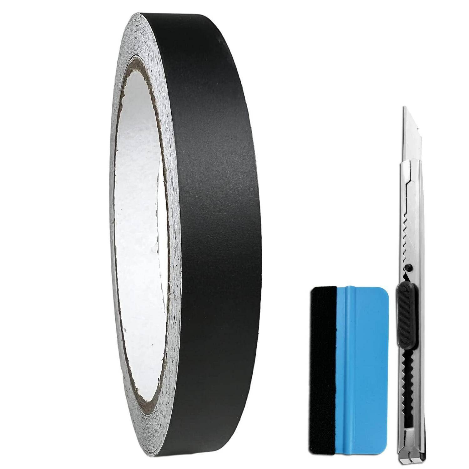 Schwarze Klebeband-Rolle, blau-schwarzes Universalmesser und kleiner Schaber auf weißem Hintergrund.