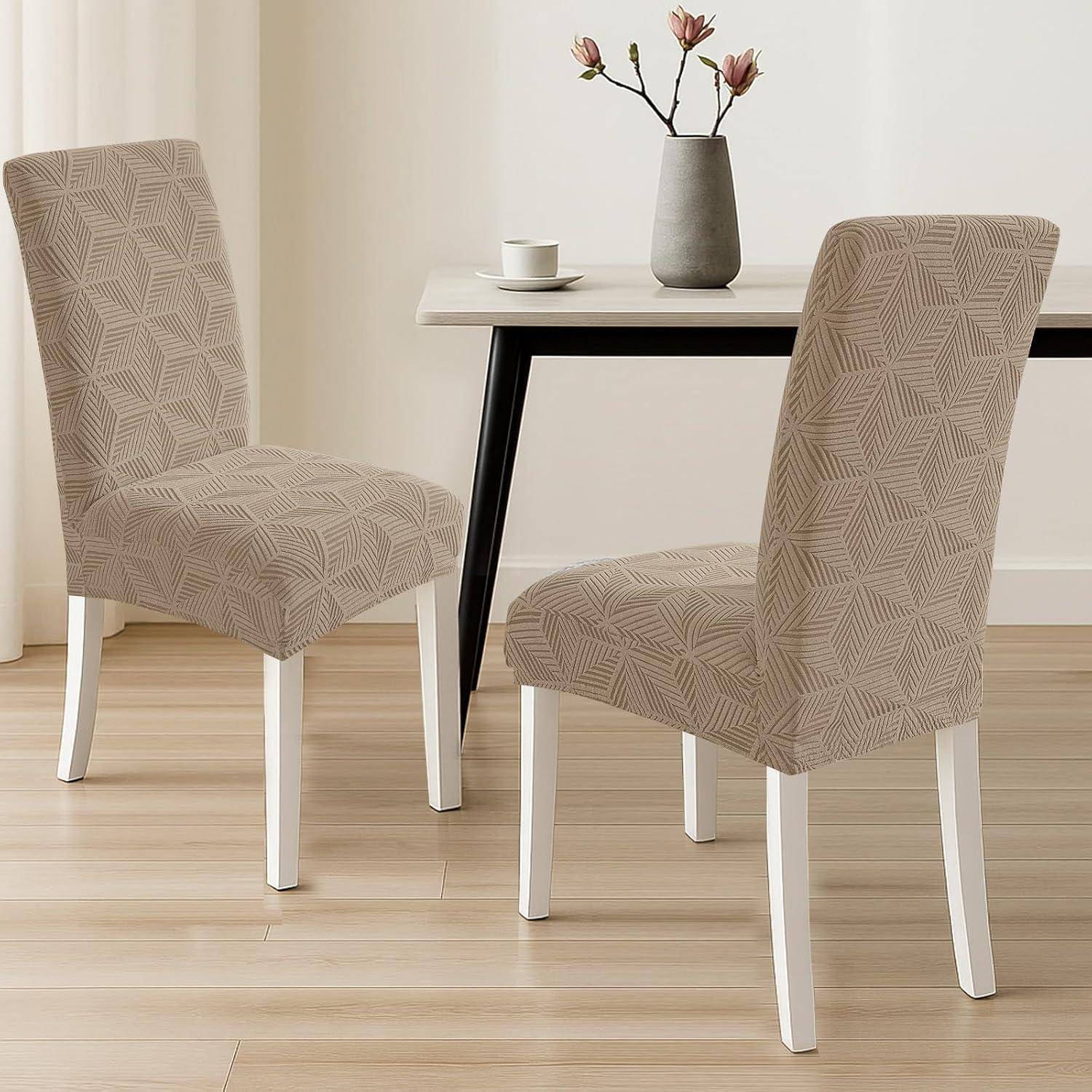 Zwei beige gemusterte gepolsterte Esszimmerstühle um einen kleinen Tisch mit einer Vase und einer Tasse in einem hellen minimalistischen Raum.
