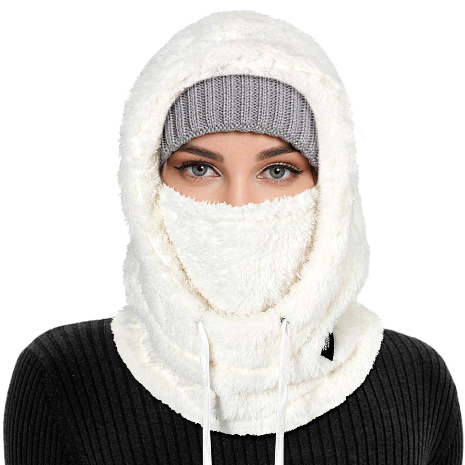 Person, das einen weißen Winter-Gesichtsmütze trägt und eine graue Strickmütze hat, wobei nur die Augen über einem schwarzen Pullover sichtbar sind.