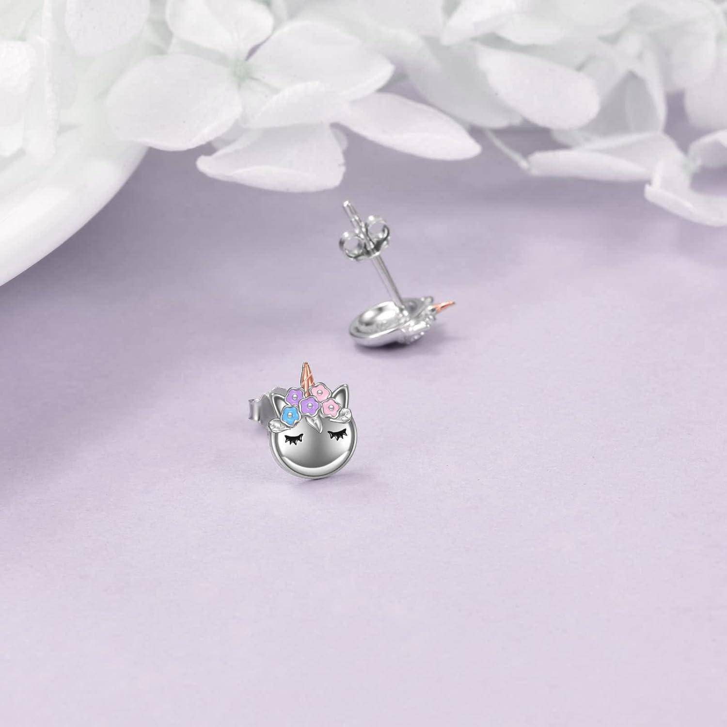 Silberne Einhorn-Stecker-Ohrringe auf zartem lavendelviolettem Hintergrund, von vorne und hinten mit pastell Blütendetail gezeigt.