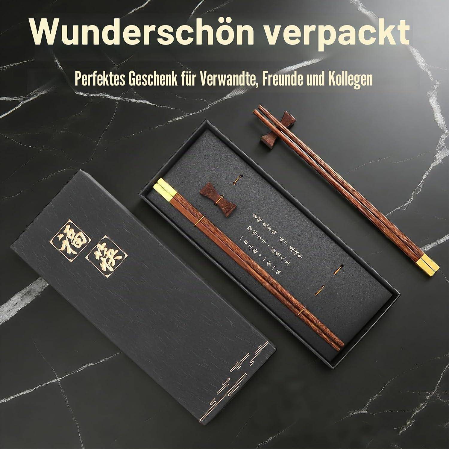 Deutsches Geschenkset mit verpackten Stäbchen und Zubehör auf einer dunklen Marmoroberfläche, beschriftet mit „Wunderschön verpackt" und „Perfektes Geschenk für Verwandte, Freunde und Kollegen"".