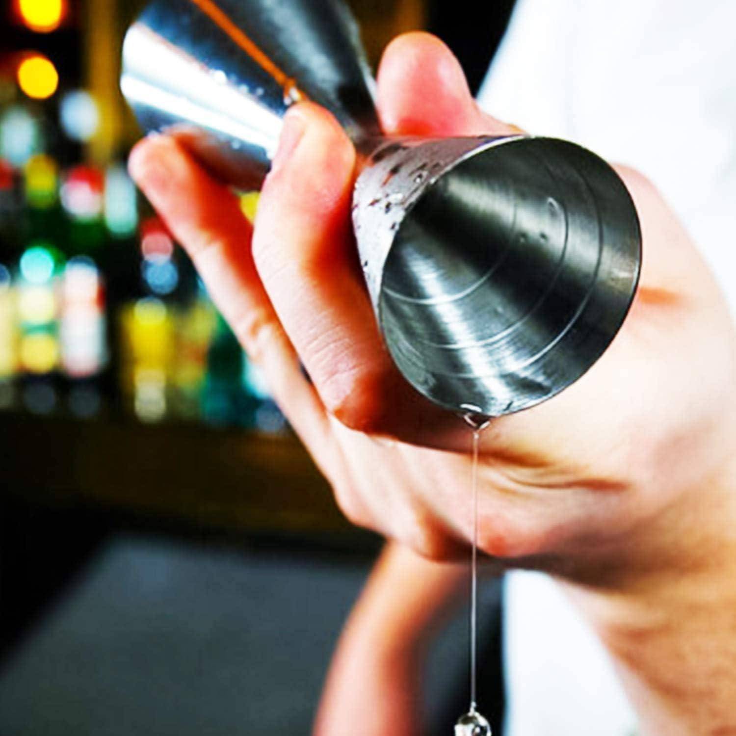 Nahaufnahme einer Hand, die einen metallenen Cocktail-Jigger hält, mit Flüssigkeit, die daraus fließt, was die Getränkezubereitung an einer Bar andeutet.