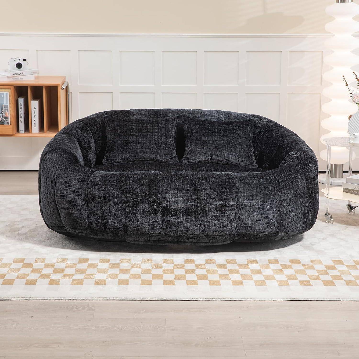 Ein dunkelgrauer übergroßes Plüsch-Zweisitzer-Sofa sitzt in einem hellen modernen Wohnzimmer auf einem gemusterten Teppich.