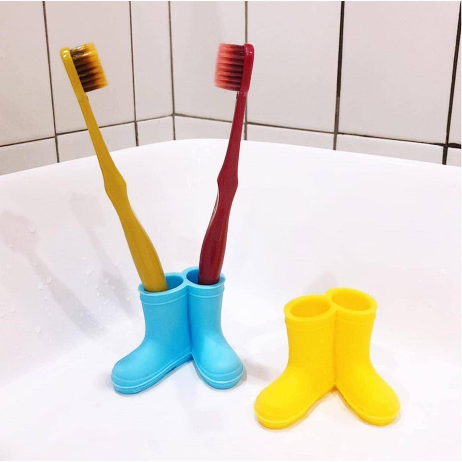 Zwei Zahnbürsten, die aufrecht in schuhförmigen Behältern stehen, eine blaue und eine gelbe, auf einem Badezimmerwaschtisch.