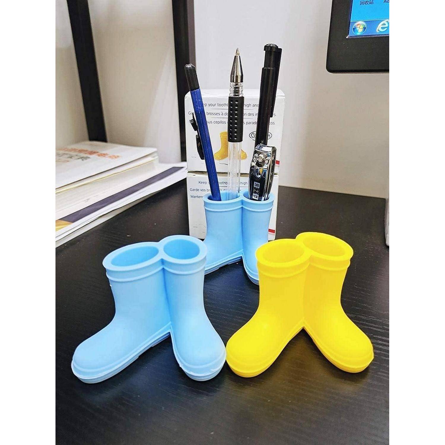 Vier neuartige stiefelförmige Stifthalter in Blau und Gelb stehen auf einem Schreibtisch und halten Stifte und einen Druckbleistift.