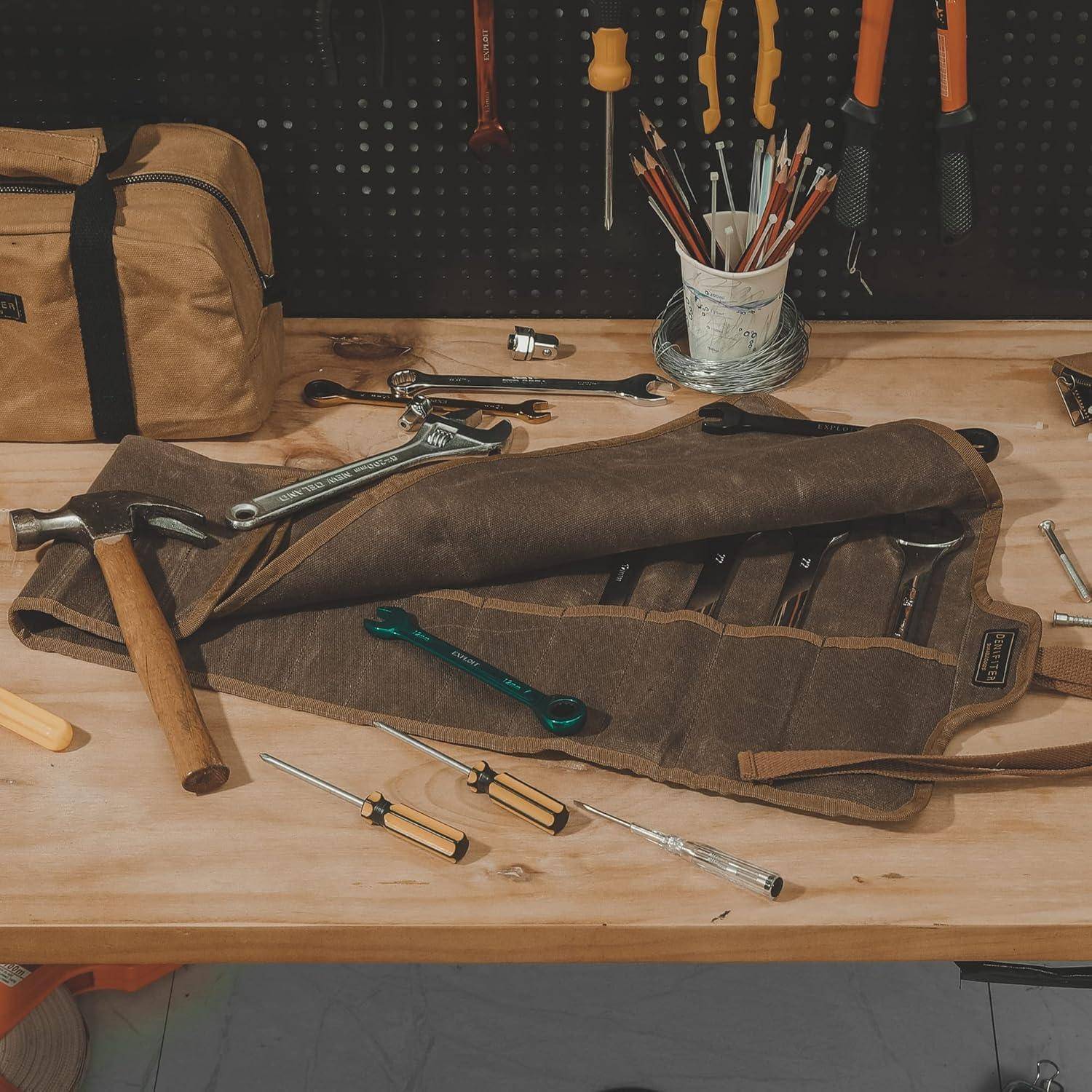 Werkzeugrolle auf einer Werkbank mit Hämmern, Schraubenschlüsseln, Schraubendrehern und Zangen, neben einer Leinwerkzeugtasche und einem Glas mit Bleistiften.