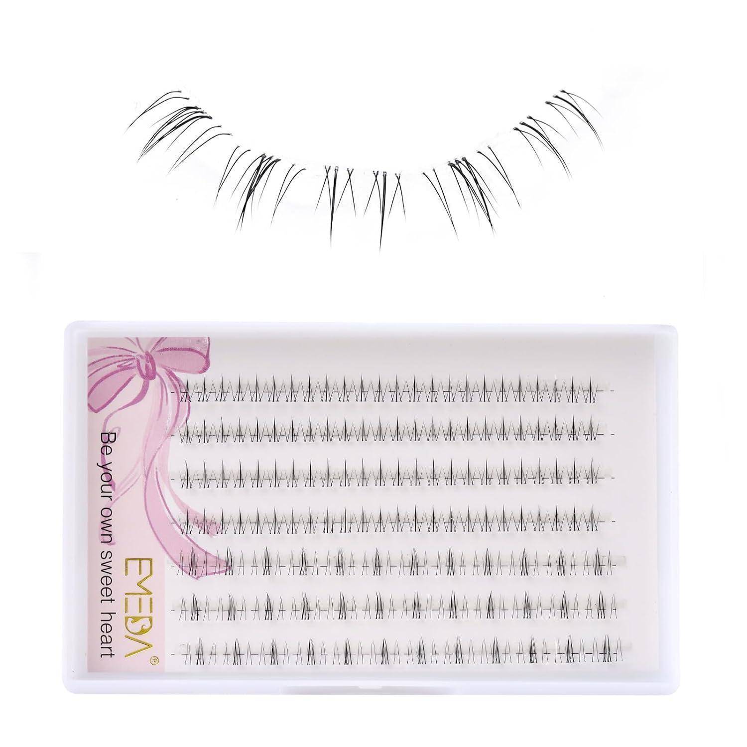Falsche Wimpernstreifen über einer Schachtel mit einzelnen künstlichen Wimpern in einem rosa beschrifteten Tablett, das die Produktverpackung und den Stil zeigt.