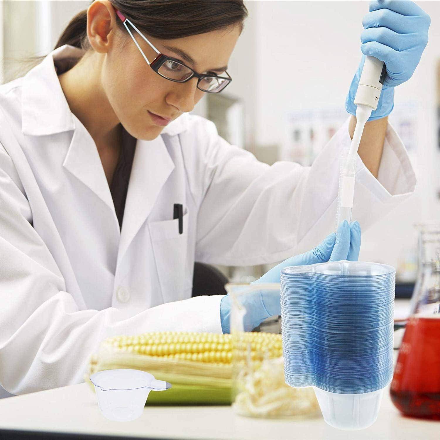 Wissenschaftler im Laborkittel und Handschuhen verwendet eine Pipette, um Flüssigkeit in ein Gestell mit blauen Probenbecher in einem Labor zu übertragen.
