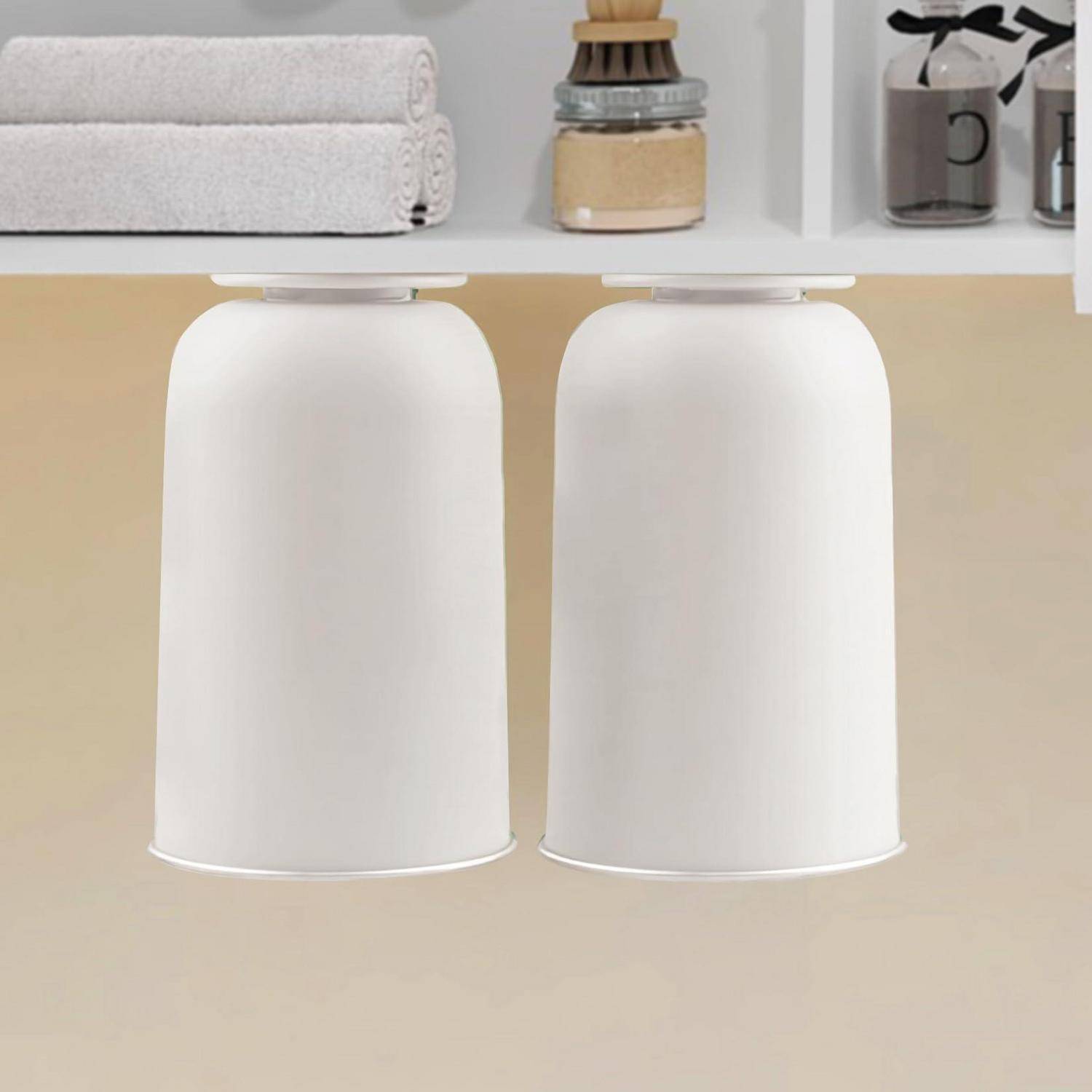Zwei weiße zylindrische hängende Aufbewahrungsbehälter oder Lampen nebeneinander unter einem Regal in einer beige gestalteten Raumumgebung aufgehängt.