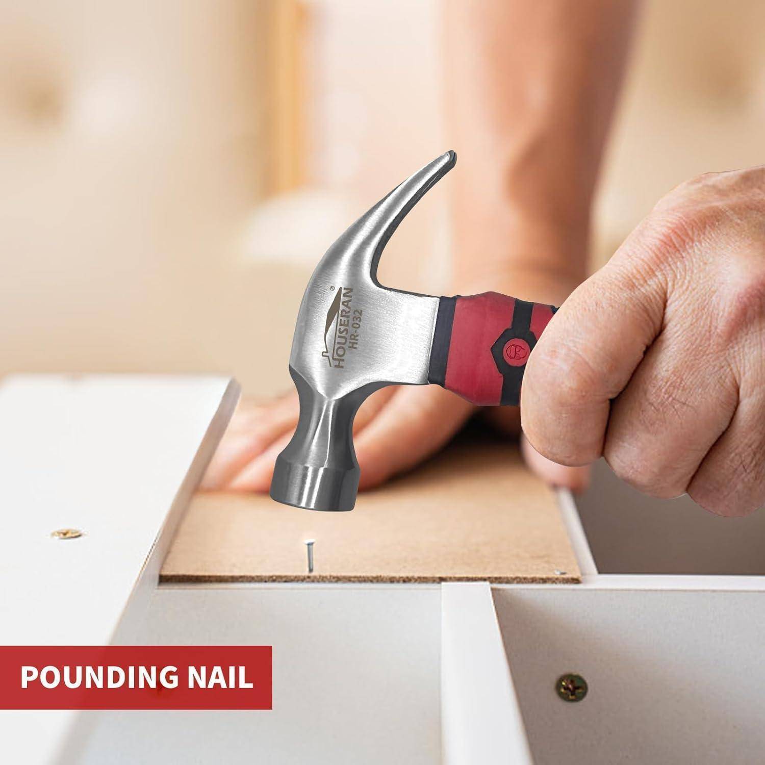 Hand, die einen Klauenhammer verwendet, um einen Nagel in ein Holzbrett während der Möbelmontage zu treiben, mit der Beschriftung „NAGEL EINSCHLAGEN