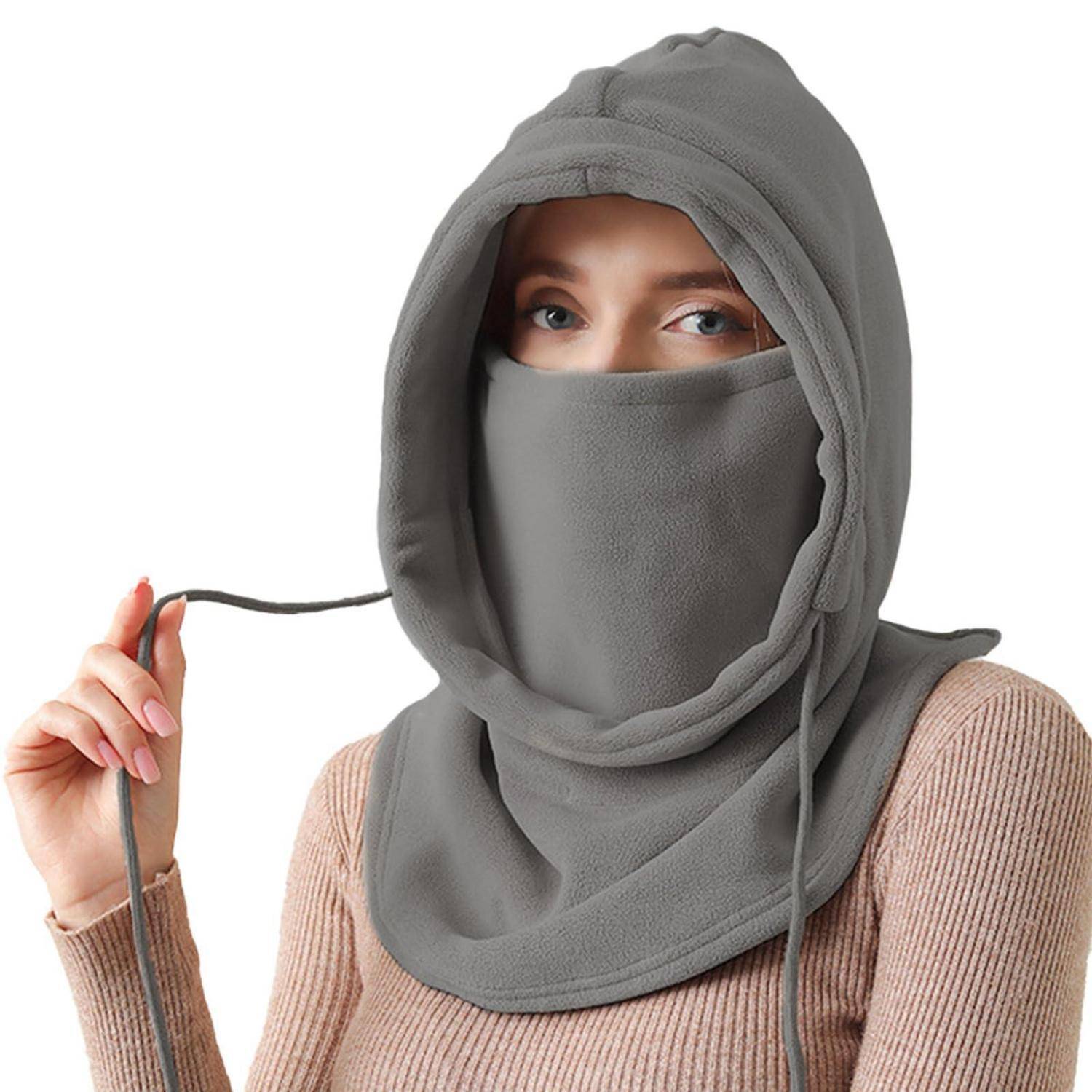 Frau, die eine graue Kapuzen-Gesichtsbedeckung trägt, die nur ihre Augen sichtbar lässt, hält die Zugschnur vor weißem Hintergrund.