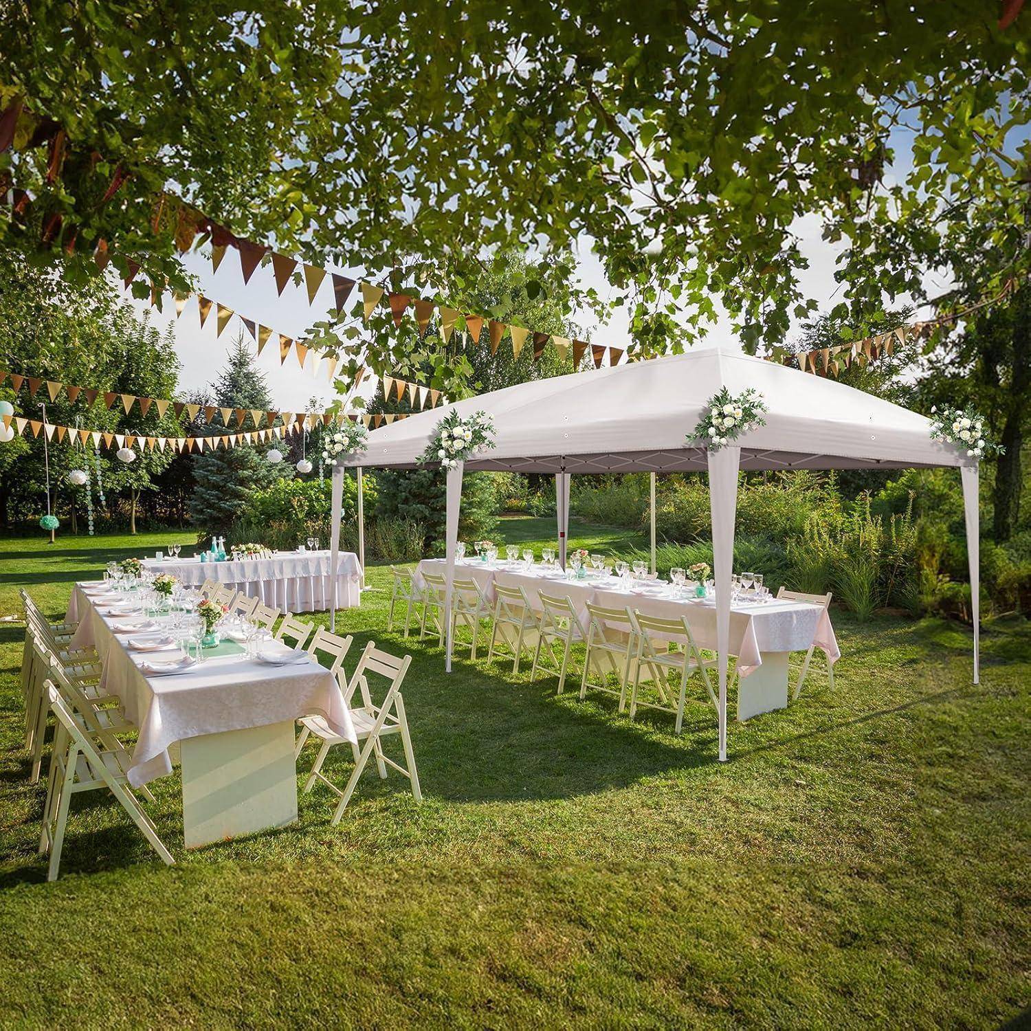 Hochzeitsempfang im Freien mit weißem Zelt, langen Esstischen, Stühlen und Girlanden unter Bäumen auf einer grünen Rasenfläche.